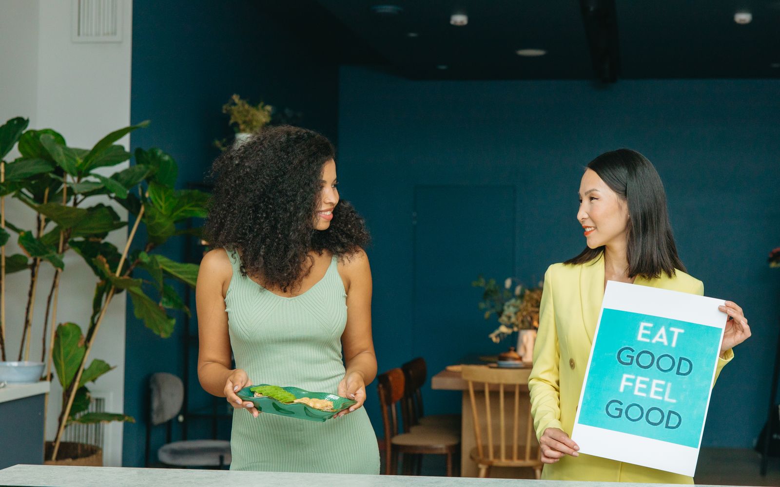 Two women talking about healthy eating with an 'Eat good, feel good' sign