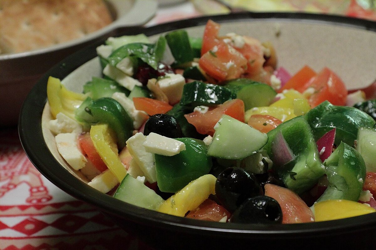 A bowl of Greek salad with tomatoes, cucumber, peppers, olives and feta