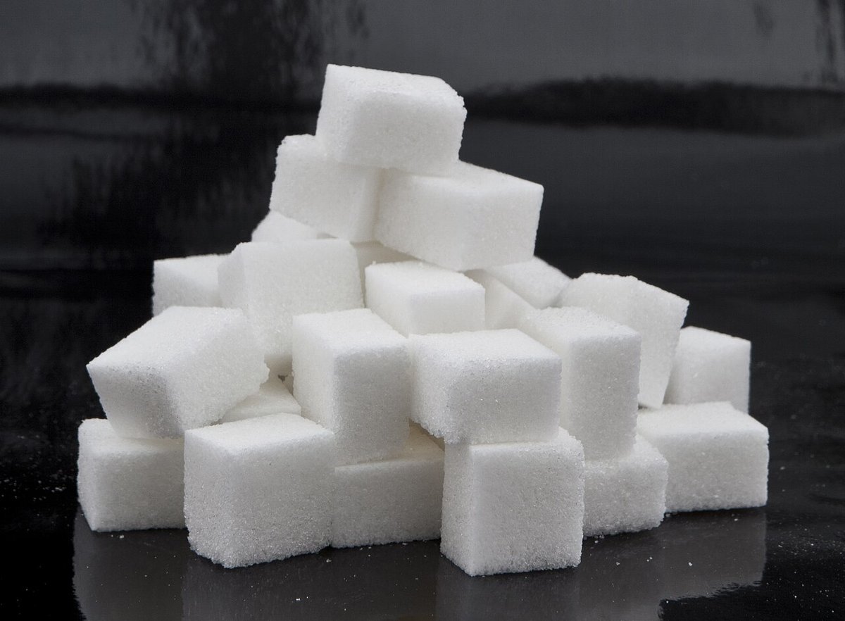 A stack of white sugar cubes on a dark surface
