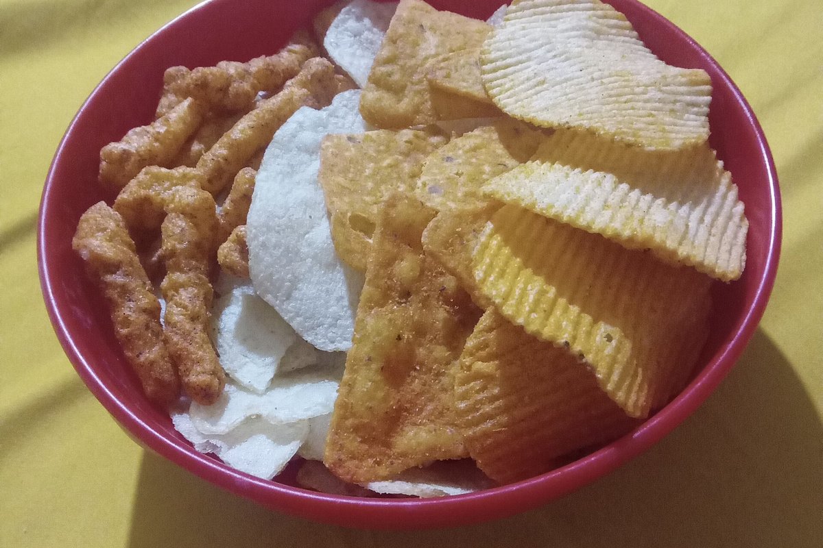 A bowl of packaged snacks: crisps, cheese puffs and tortilla chips